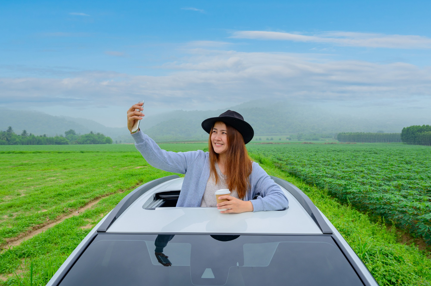 asian woman with mobile phone standing out car sunroof relaxing freedom with spring time young tourist travel alone thailand summer holiday